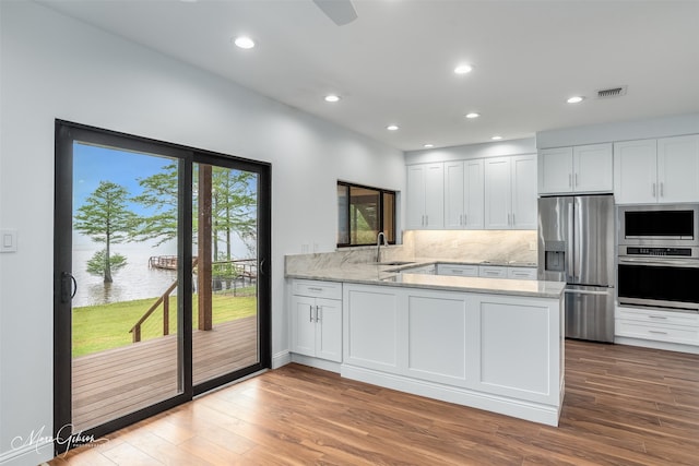 kitchen with kitchen peninsula, appliances with stainless steel finishes, white cabinetry, and sink