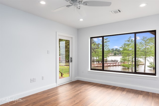 empty room featuring ceiling fan, a water view, and hardwood / wood-style flooring