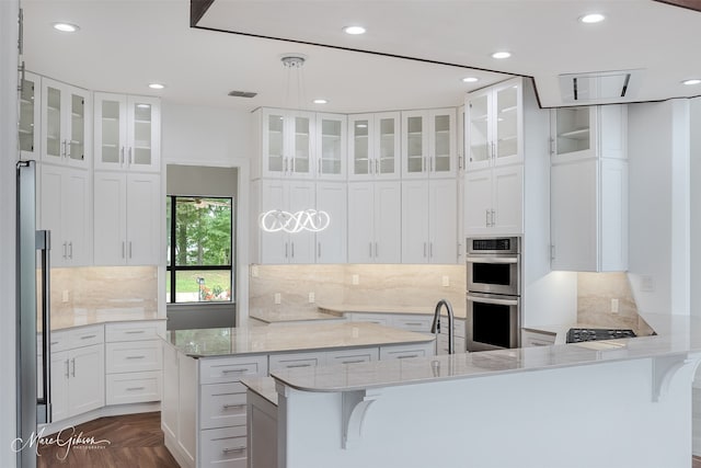 kitchen featuring white cabinetry, a center island, stainless steel double oven, dark parquet floors, and a breakfast bar area