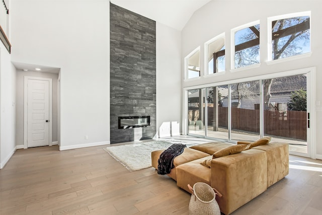 living room featuring hardwood / wood-style flooring, a towering ceiling, and a fireplace