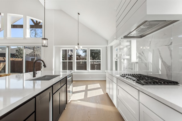 kitchen featuring high vaulted ceiling, decorative light fixtures, stainless steel appliances, white cabinetry, and light wood-type flooring