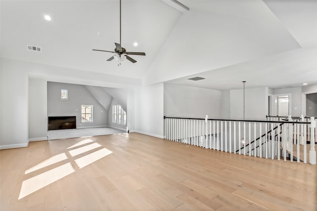 spare room featuring high vaulted ceiling, beam ceiling, ceiling fan, and light hardwood / wood-style floors