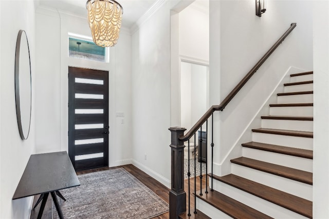 entryway with dark hardwood / wood-style floors, a notable chandelier, and crown molding