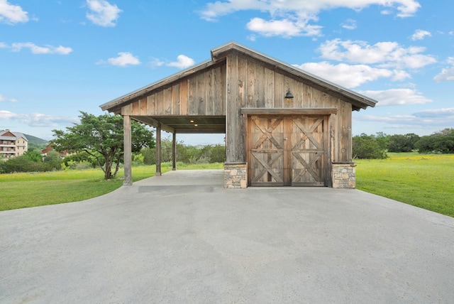 garage with wood walls, a carport, and a lawn