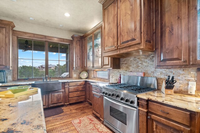 kitchen with oven, wood-type flooring, light stone countertops, a kitchen island, and a stone fireplace