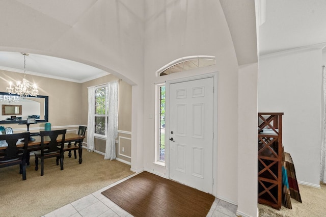 foyer featuring an inviting chandelier, crown molding, and light tile floors