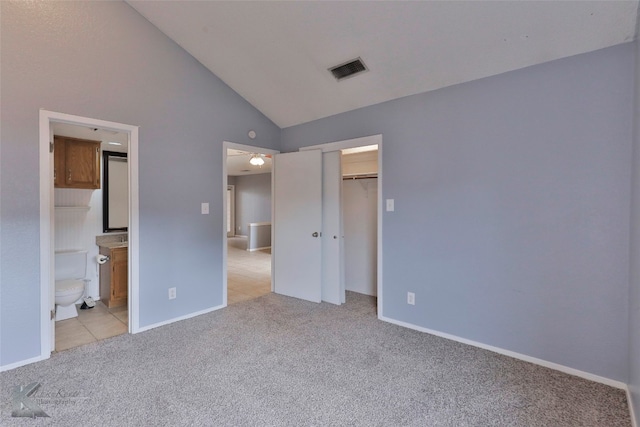 unfurnished bedroom with light colored carpet, connected bathroom, a closet, and high vaulted ceiling