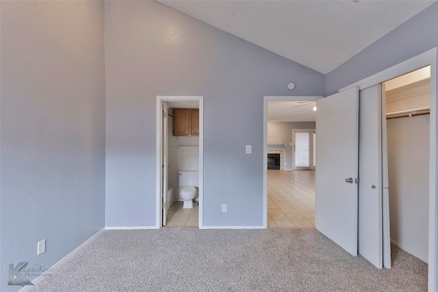 unfurnished bedroom with light colored carpet, a closet, ensuite bath, and high vaulted ceiling