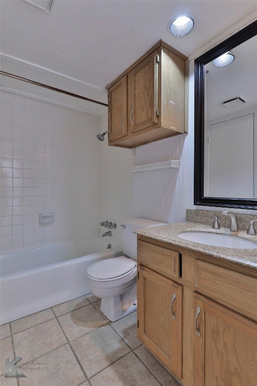 full bathroom with tile floors, vanity, tiled shower / bath combo, and toilet