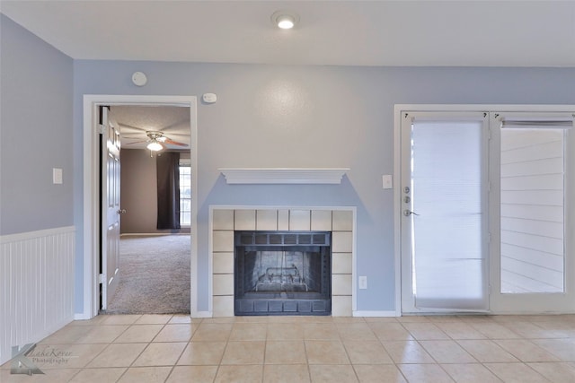 unfurnished living room featuring a tile fireplace, ceiling fan, and light tile flooring