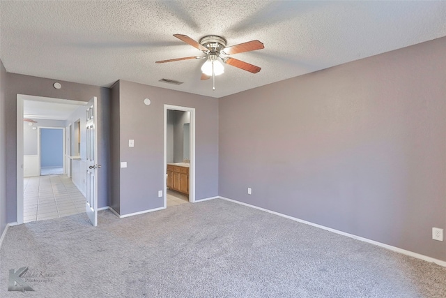 unfurnished bedroom featuring a textured ceiling, ceiling fan, light carpet, and connected bathroom