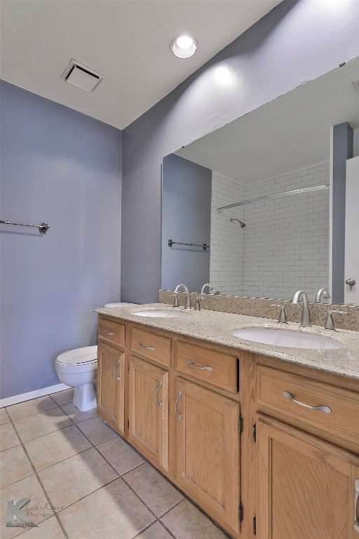 bathroom with dual bowl vanity, tile floors, and toilet