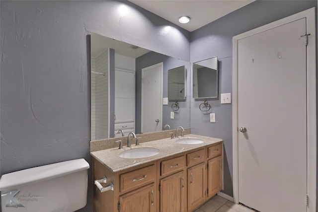 bathroom with double vanity, toilet, and tile floors