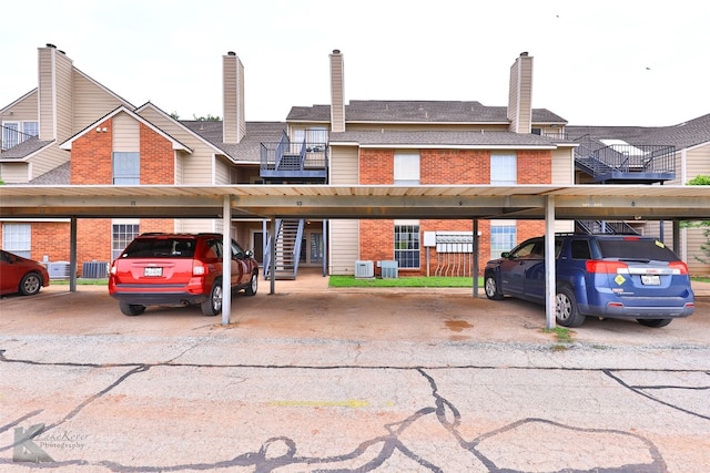 view of front of home with a carport, a balcony, and central AC unit