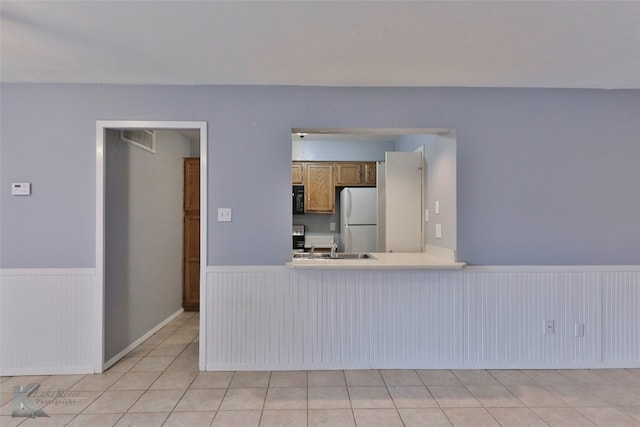 kitchen featuring sink, light tile flooring, and white fridge