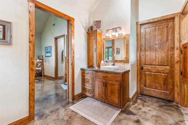 bathroom with high vaulted ceiling, vanity with extensive cabinet space, and concrete flooring