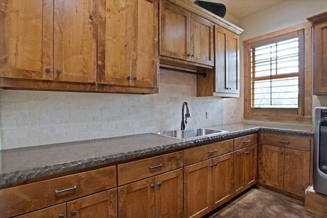 205 Haciendas Dr, Weatherford, TX 76087 - kitchen featuring a sink, brown cabinetry, backsplash, dark stone counters, and washer / dryer
