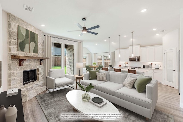 living room with ceiling fan, sink, a fireplace, and light hardwood / wood-style floors