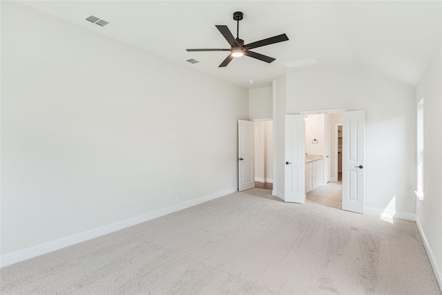 unfurnished bedroom featuring vaulted ceiling, light colored carpet, ceiling fan, and ensuite bath