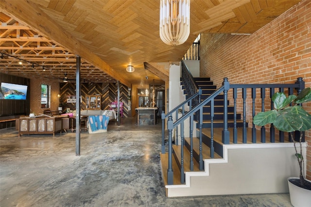 stairway with a notable chandelier and brick wall