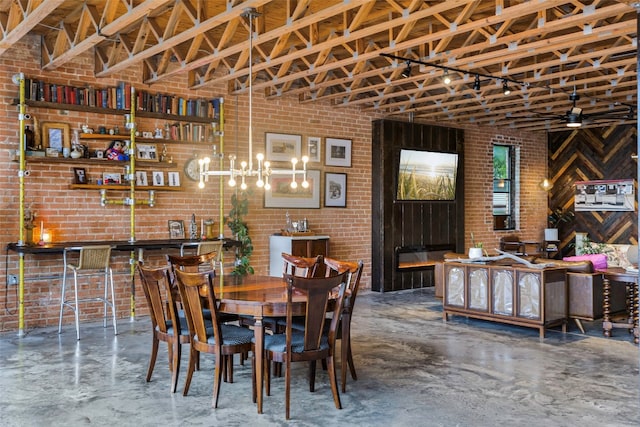 dining room featuring ceiling fan with notable chandelier and brick wall