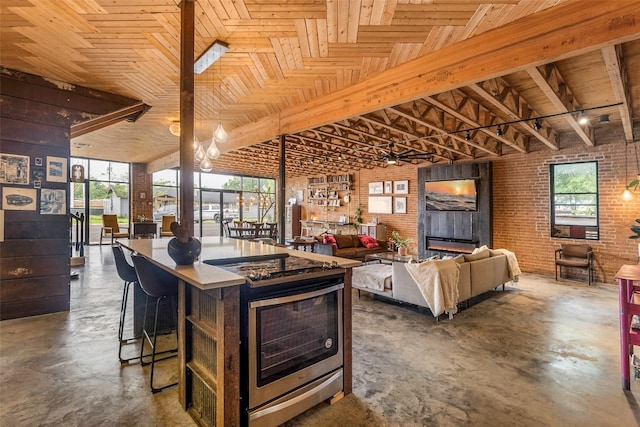 kitchen featuring a kitchen island, hanging light fixtures, brick wall, wood ceiling, and a breakfast bar