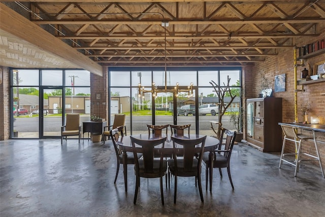 unfurnished dining area with brick wall, a towering ceiling, and an inviting chandelier