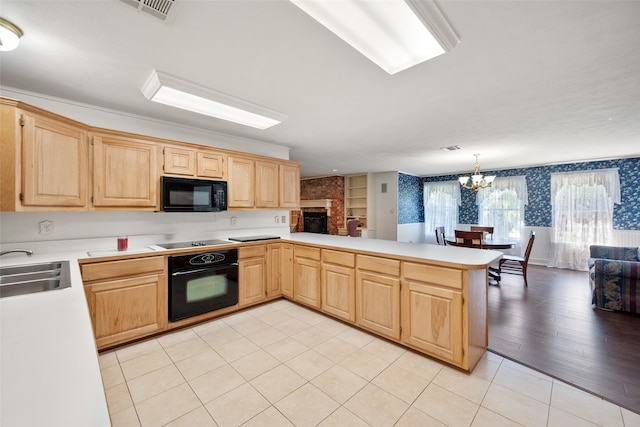 kitchen featuring black appliances, pendant lighting, sink, light hardwood / wood-style floors, and kitchen peninsula