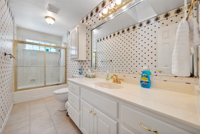 full bathroom featuring toilet, bath / shower combo with glass door, vanity, and tile patterned floors