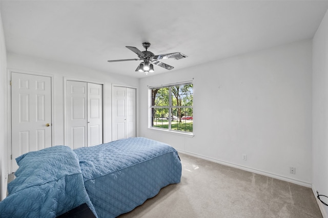 bedroom featuring multiple closets, carpet floors, and ceiling fan