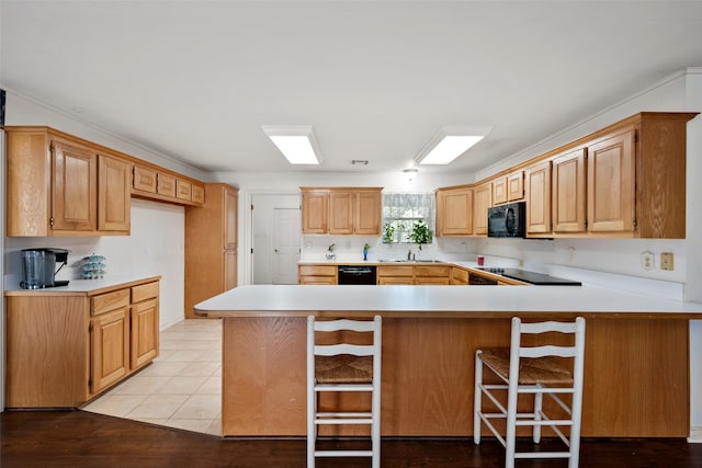 kitchen featuring kitchen peninsula, black appliances, a breakfast bar area, and sink