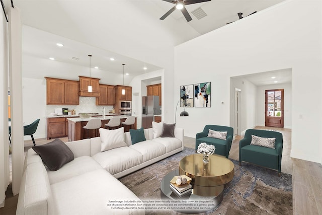 living room with a high ceiling, hardwood / wood-style floors, and ceiling fan