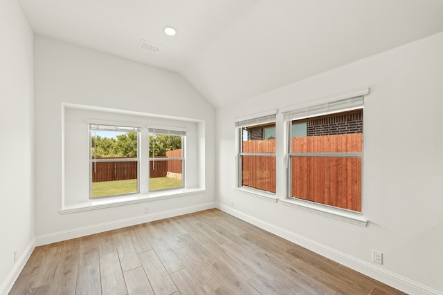 empty room with light hardwood / wood-style floors and lofted ceiling