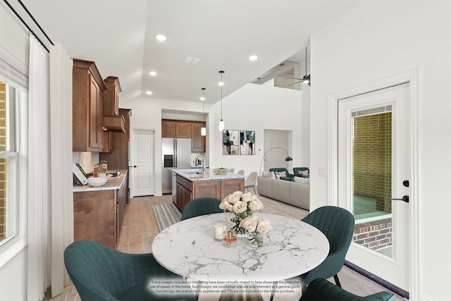 dining area featuring light wood-type flooring, vaulted ceiling, sink, and ceiling fan