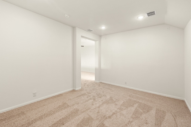 carpeted spare room featuring vaulted ceiling