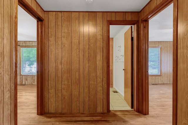 corridor featuring wooden walls and light hardwood / wood-style flooring