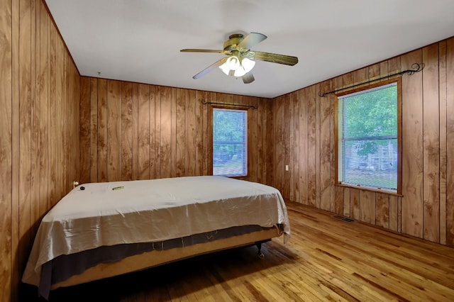 bedroom featuring wood walls, light wood-type flooring, and ceiling fan