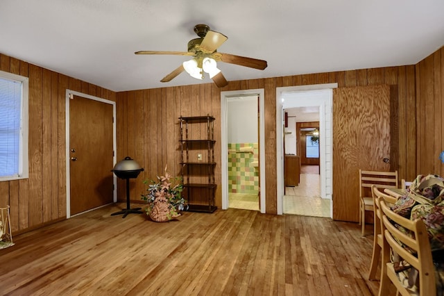 living area with ceiling fan, hardwood / wood-style flooring, and wood walls