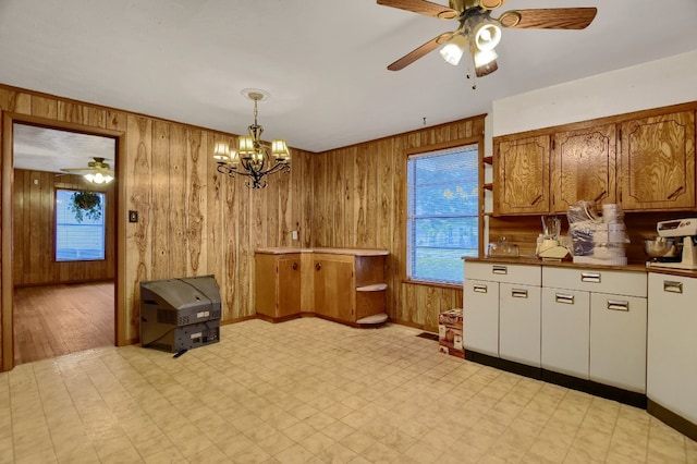 kitchen with wood walls, decorative light fixtures, ceiling fan with notable chandelier, and light wood-type flooring