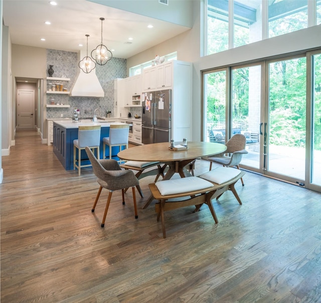 dining room featuring an inviting chandelier, hardwood / wood-style floors, sink, and a high ceiling