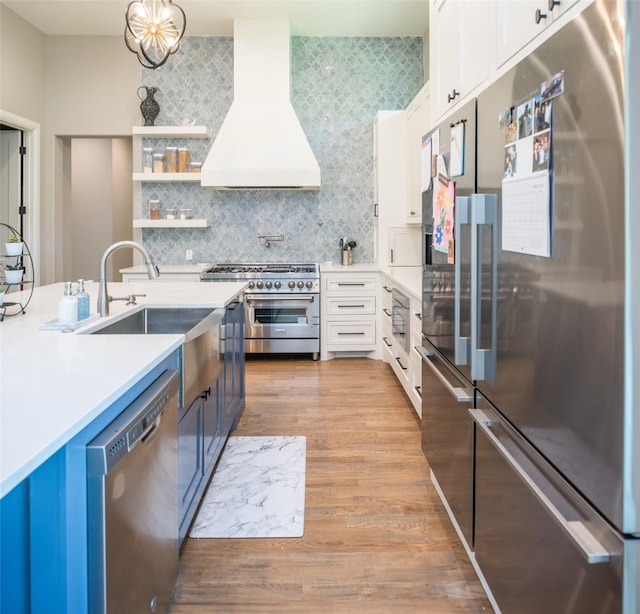 kitchen with sink, white cabinetry, hanging light fixtures, high quality appliances, and custom range hood