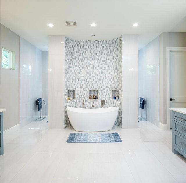 bathroom with tile patterned flooring, vanity, tile walls, and a tub to relax in