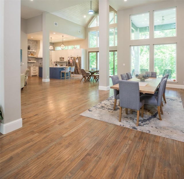 dining space featuring wood-type flooring and high vaulted ceiling