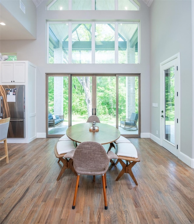 dining space featuring high vaulted ceiling and light hardwood / wood-style flooring