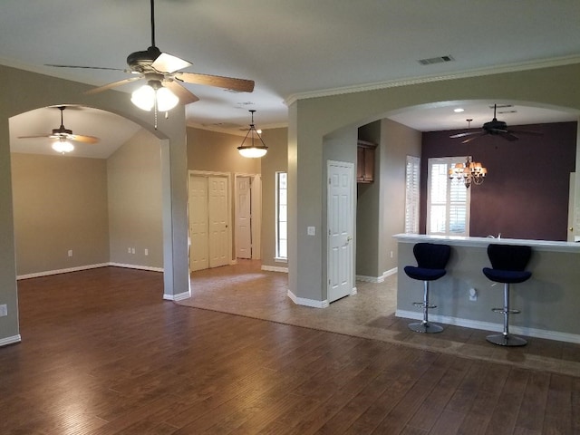 unfurnished living room with ceiling fan with notable chandelier, dark hardwood / wood-style floors, crown molding, and indoor bar