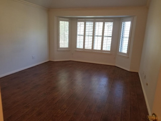 unfurnished room with dark wood finished floors, baseboards, and crown molding