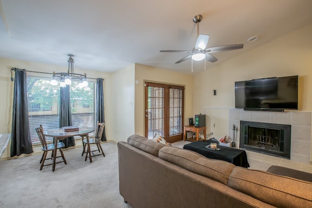 living room featuring light colored carpet, vaulted ceiling, a tiled fireplace, and a healthy amount of sunlight