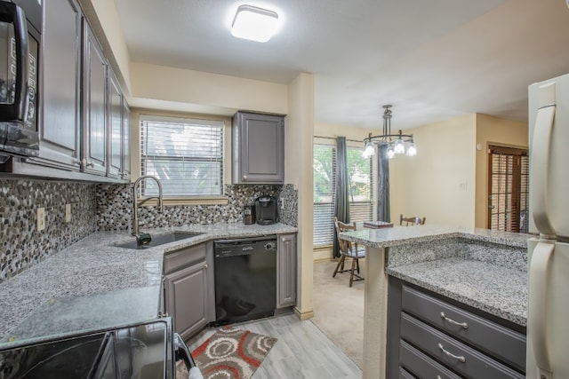 kitchen featuring light stone countertops, backsplash, hanging light fixtures, black dishwasher, and sink