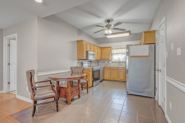 kitchen featuring ceiling fan, sink, backsplash, stainless steel appliances, and vaulted ceiling