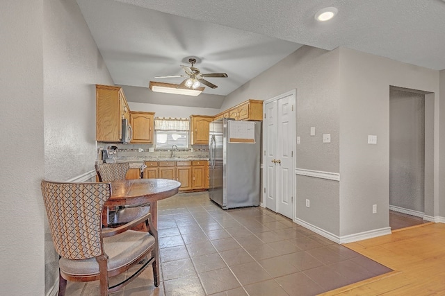 kitchen with ceiling fan, sink, backsplash, stainless steel appliances, and vaulted ceiling